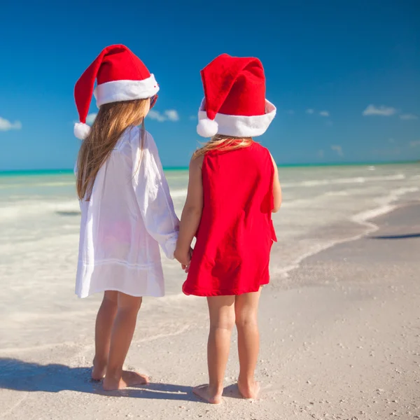 Little cute girls in Christmas hats on the exotic beach — Stok fotoğraf